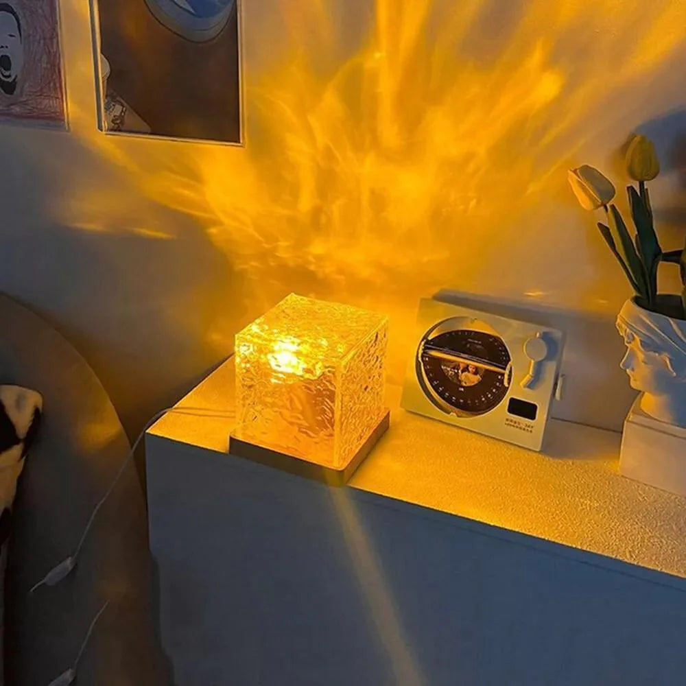 Yellow light cube on a surface with a clock and plant in the background