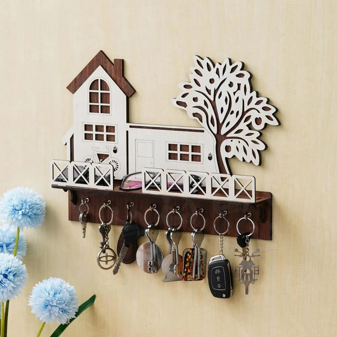 Key holder with house and tree design on a wall, featuring various keys.