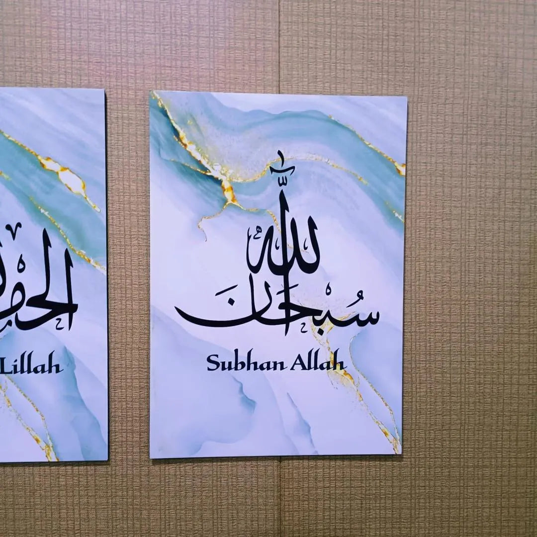 Two posters with Arabic calligraphy on a marble background, displayed against a textured wall.