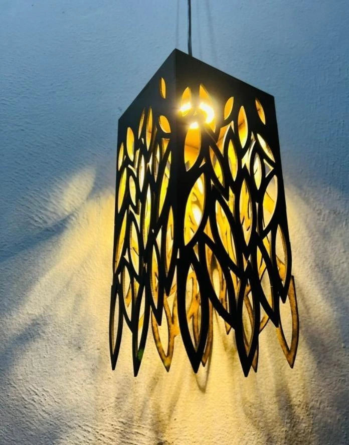 Modern pendant light with leaf-like cutouts on a textured wall.