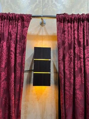 Maroon curtains with floral pattern on a beige wall