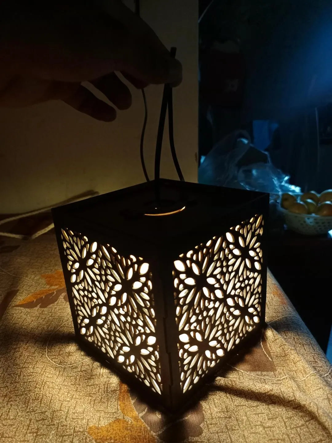 Decorative lantern with intricate cut-out patterns on a textured surface.