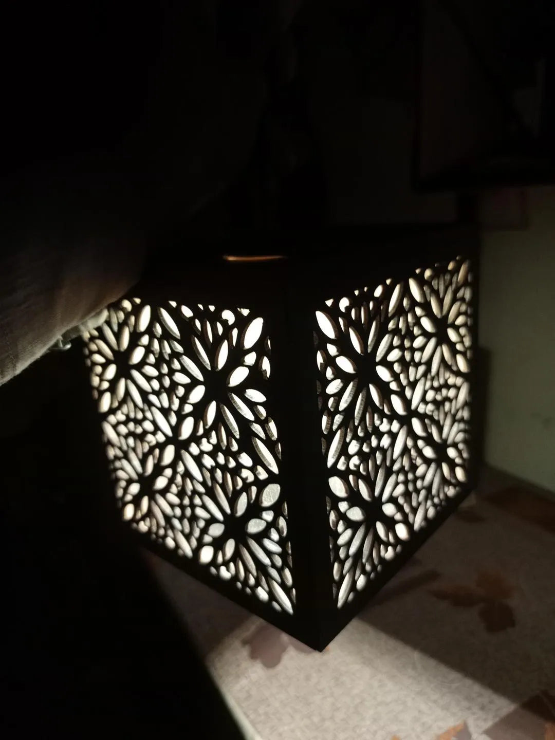 Decorative lantern with intricate cut-out patterns on a dark background