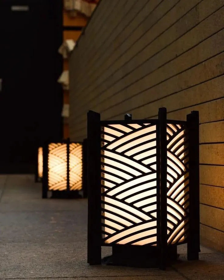 Decorative outdoor lanterns with wavy pattern on a wooden wall.