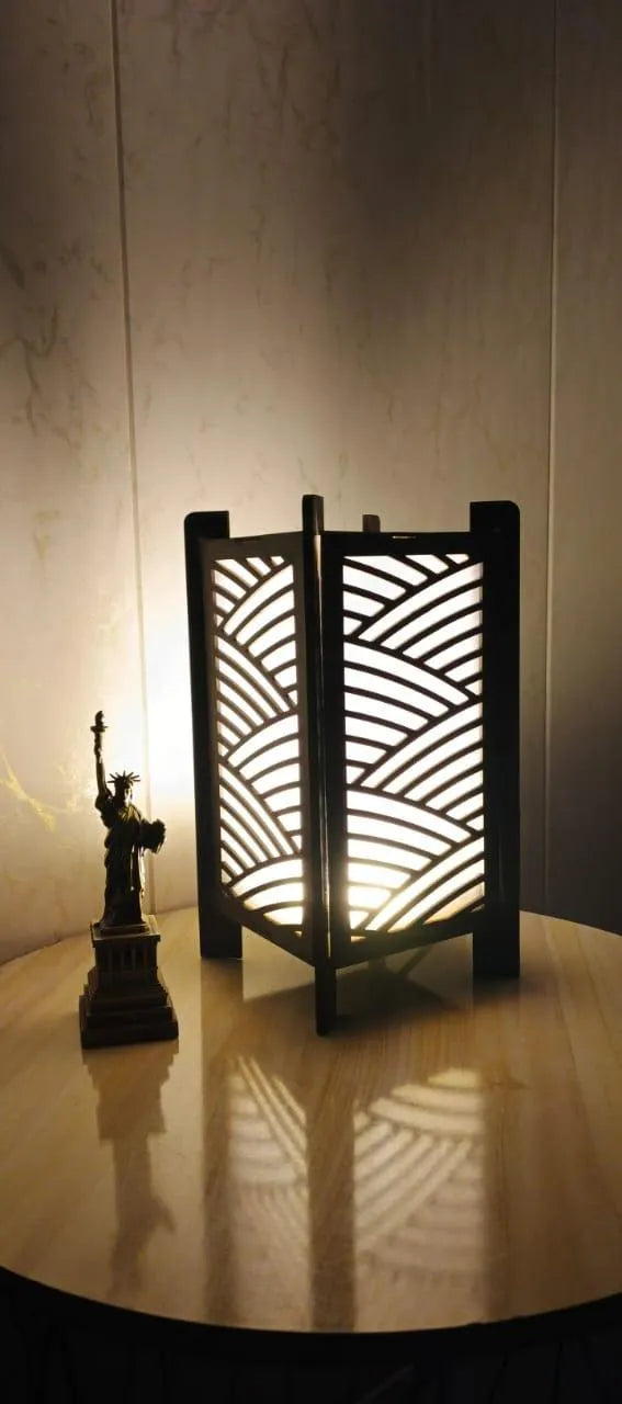Decorative lantern with wavy pattern on a wooden surface, illuminated by a light source.