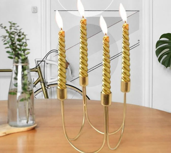 Gold candle holder with lit candles on a wooden surface