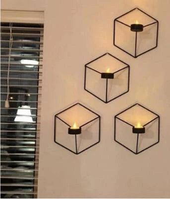 Four geometric wall sconces with candles on a wall.