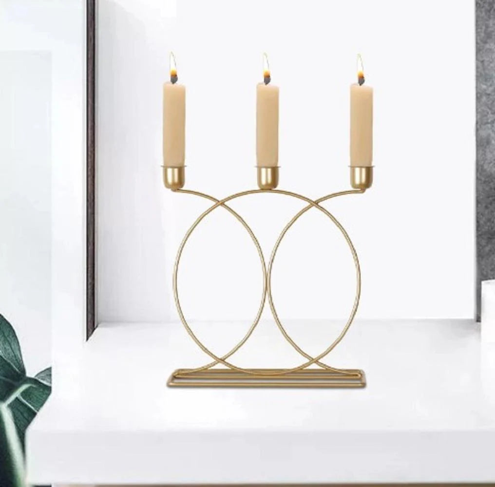 Gold candle holder with three candles on a white surface