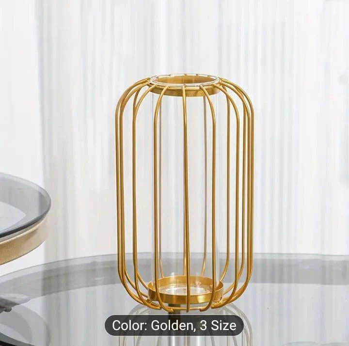 Gold metal candle holder on a glass table with white curtains in the background
