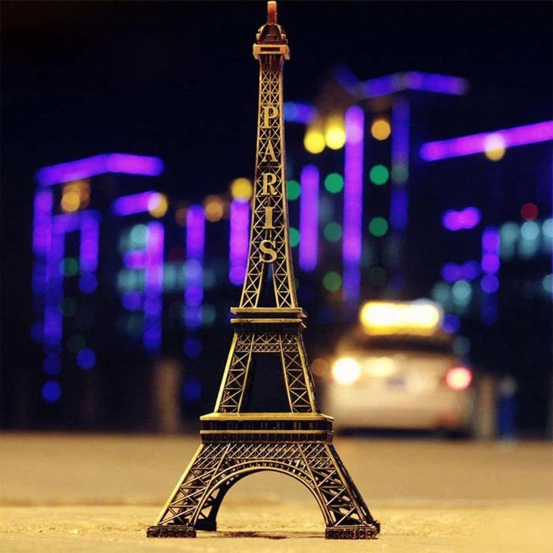 Model of the Eiffel Tower with blurred city lights in the background