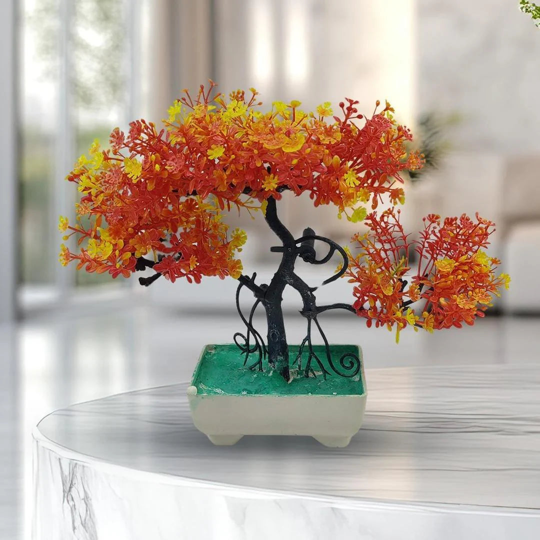 Decorative bonsai tree with orange and yellow leaves on a green base in a blurred indoor setting