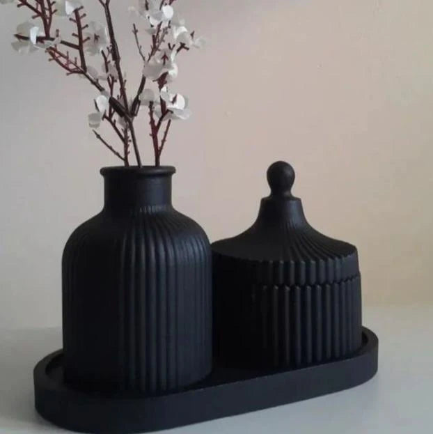 Two black textured vases on a matching black stand with white flowers.