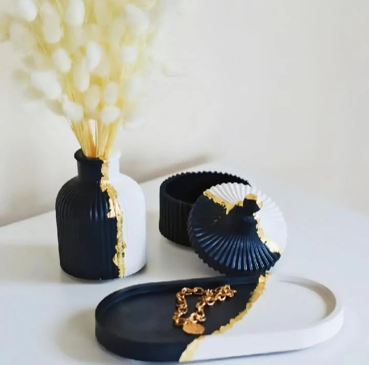 Decorative black and gold vases and containers on a white surface
