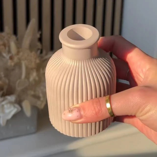 Hand holding a ribbed beige ceramic vase with a blurred background