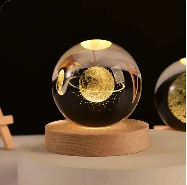 Glass sphere with planetary design on a wooden base against a dark background
