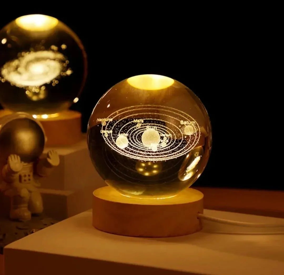 Glowing crystal ball with solar system model on a wooden base