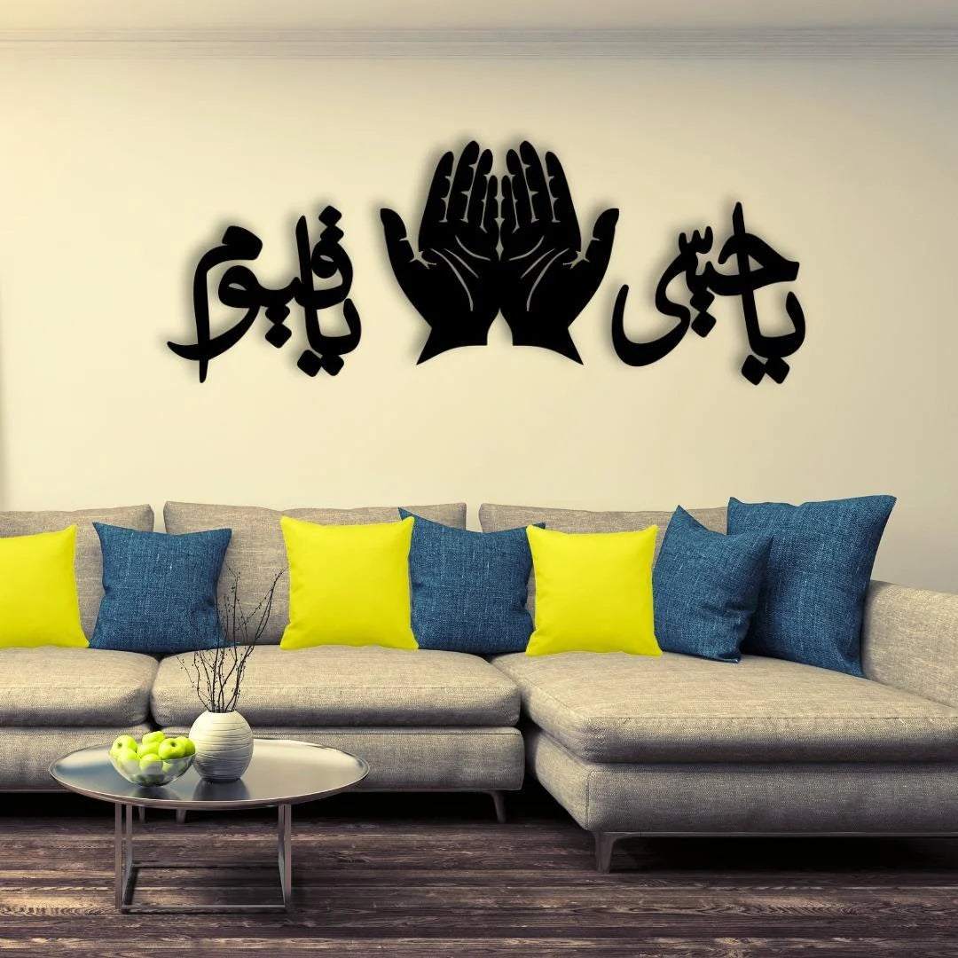 Gray sectional sofa with colorful pillows and a decorative wall piece featuring hands and Arabic text.