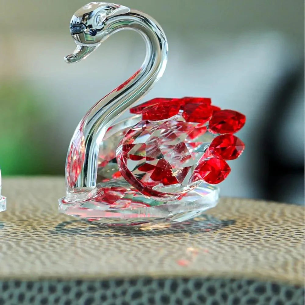 Crystal swan figurine with red gemstones on a textured surface