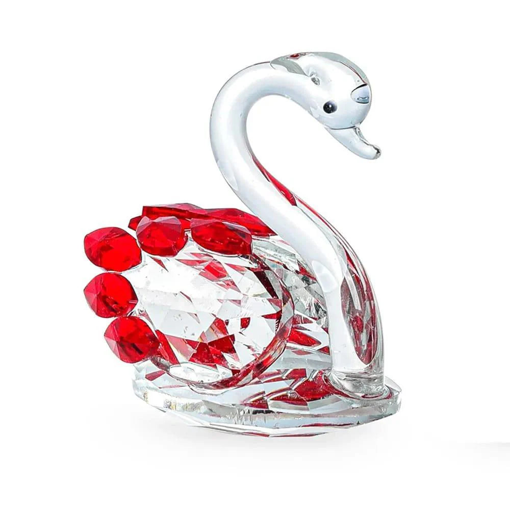 Glass swan figurine with red gemstones on a white background