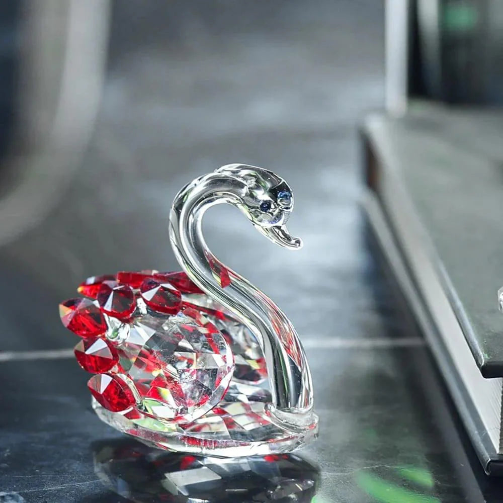 Crystal swan ornament with red gemstones on a reflective surface