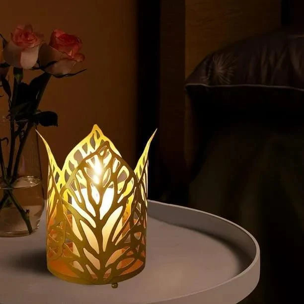 Decorative candle holder with cut-out design on a table next to a vase of flowers.