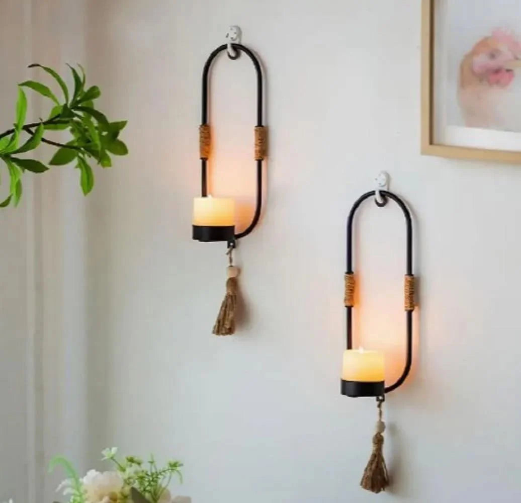 Two wall-mounted candle holders with tassels on a light-colored wall.